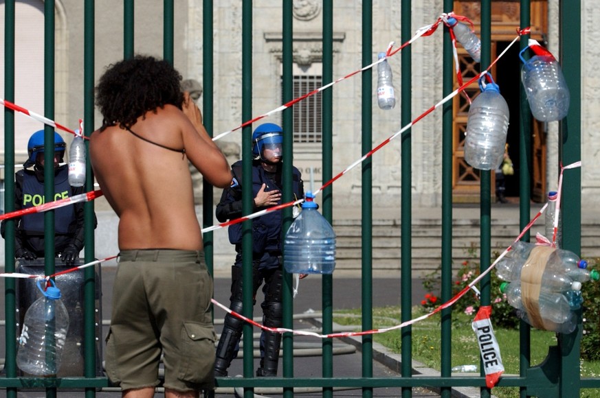 A anti-G8 demonstrator stands in front of the well watched iron bars of the World Trade Organization (WTO) building in Geneva, Switzerland, Monday, June 2, 2003, in a protest for free water for everyo ...