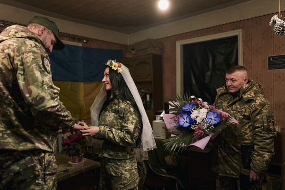 Ukrainian army medics Eugenia and Oleksander, left, exchange rings during their wedding ceremony in Lyman, Donetsk region, Ukraine, Saturday, Dec. 24, 2022. (AP Photo/Felipe Dana)