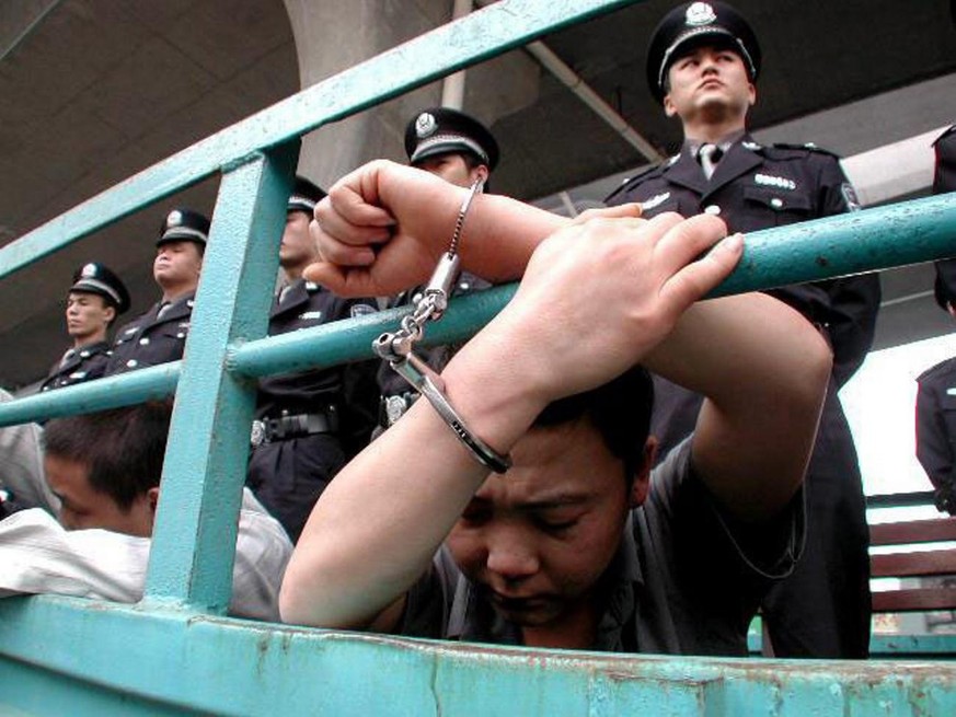 A group of condemned Chinese criminals are handcuffed and guarded by local police, waiting for an open sentence in Xuyi County in eastern China