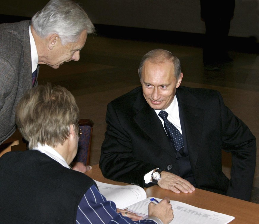 Russian President Vladimir Putin, right, speaks with local election commission officials while obtaining his ballot paper at a polling station in Moscow, Sunday, Dec.4, 2005. Muscovites went to the po ...