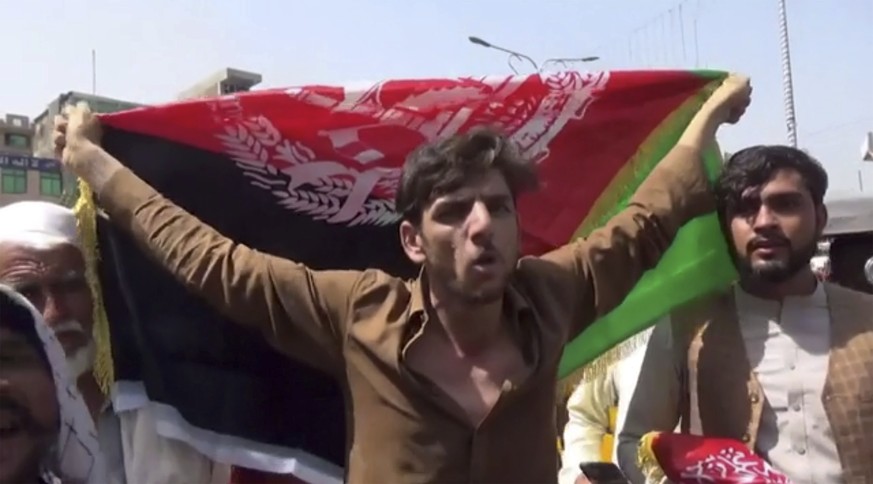 A man holds the flag of Afghanistan during a protest in Jalalabad on Wednesday, Aug. 18, 2021. Taliban militants have attacked protesters in eastern Afghanistan who dared to take down their banner and ...