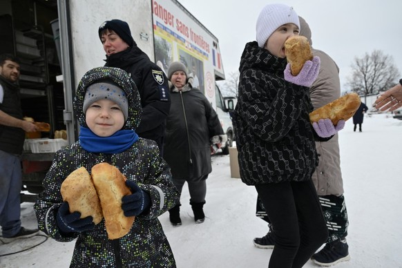Children hold loaves of freshly baked bread distributed by French volunteer baker Loic Nervi from his mobile bakery among residents of a temporary dwelling for people who lost their homes and internal ...