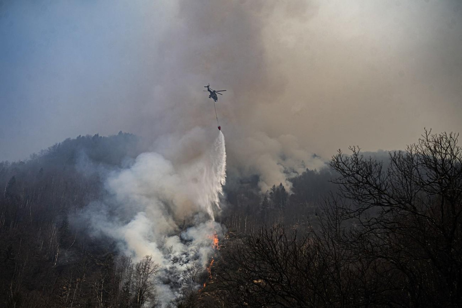 Un hélicoptère lors de travaux d'extinction d'incendie de forêt au-dessus de Verdasio dans la vallée des Centovalli, le 25 mars 2022.