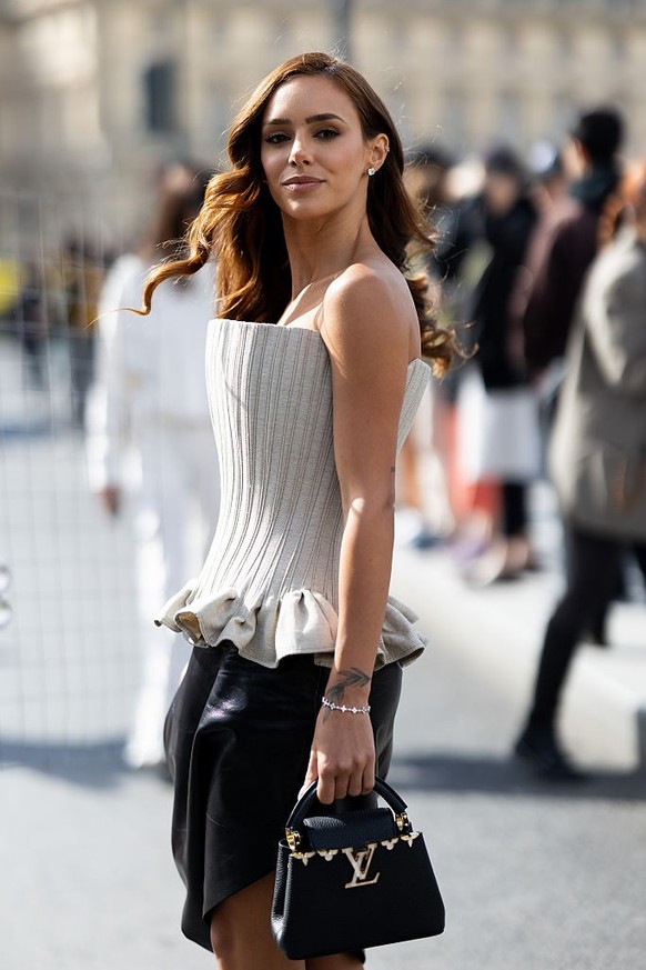 PARIS, FRANCE - MARCH 10: Bruna Biancardi wears a beige corset with ruffles, diamond earrings, a black mini asymmetric skirt, a diamond bracelets and a black leather Louis Vuitton outside Louis Vuitto ...