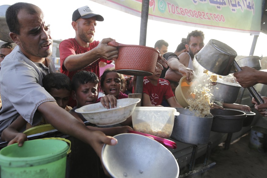 CORRECTS LOCATION TO KHAN YOUNIS - Palestinians collect food aid ahead of the upcoming Eid al-Adha holiday in Khan Younis, Gaza Strip, Saturday, June 15, 2024. (AP Photo/Jehad Alshrafi)