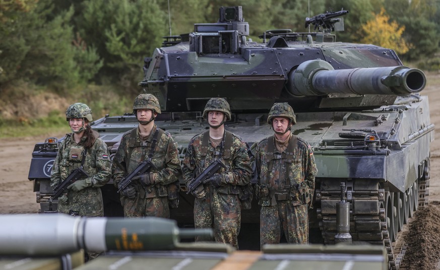 epa10248366 Soldiers stand next to a Leopard 2 battle tank during a media presentation for the annual Land Operation Exercise of the German armed forces Bundeswehr in Bergen, northern Germany, 17 Octo ...