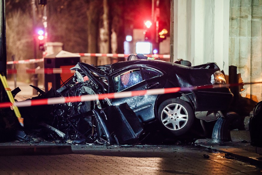epa10407956 Police officers investigate a destroyed car near a column of the Brandenburg Gate in Berlin, Germany, 16 January 2023. According to a social media release by Berlin police, a passenger car ...