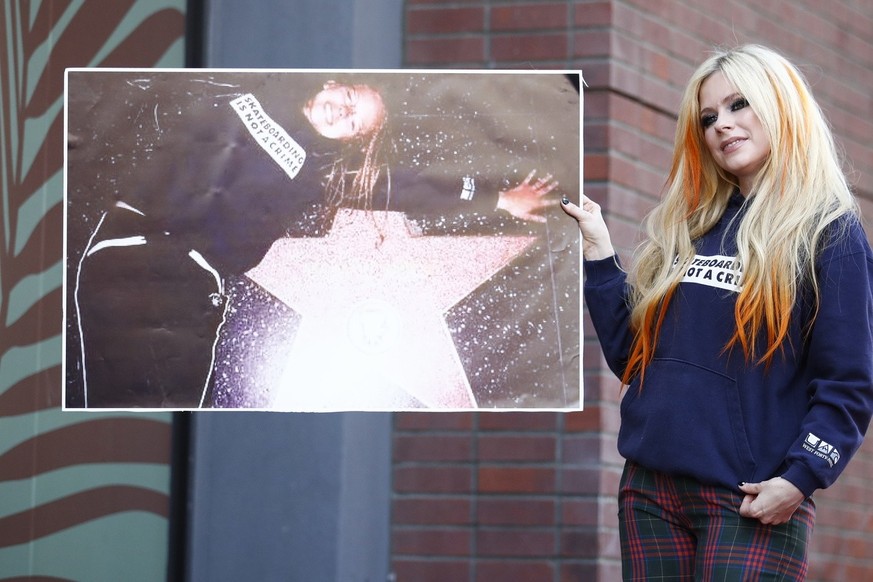 epa10150871 Canadian musician Avril Lavigne holds up a photo of her posing with a Hollywood Walk of Star from her youth during a ceremony to unveil her Hollywood Walk of Fame star in Los Angeles, USA, ...