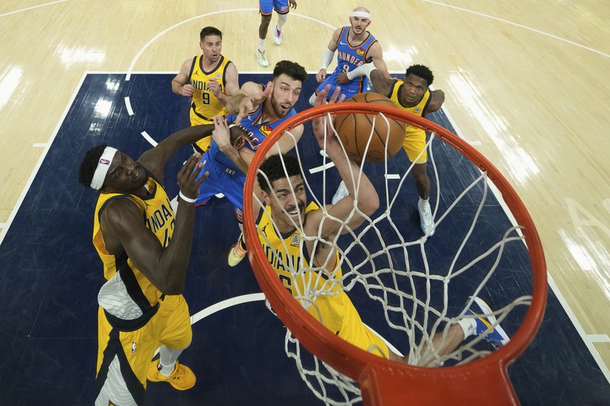 Oklahoma City Thunder forward Chet Holmgren, center, battles Indiana Pacers guard Ben Sheppard, front, for the ball during the first half of Game 3 of the NBA Finals basketball series, Wednesday, June ...