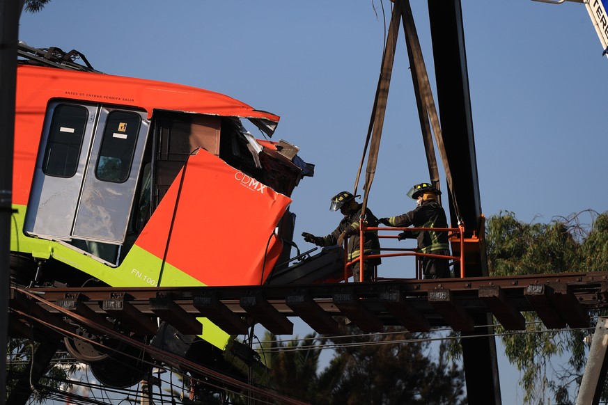 epa09177511 Workers remove one of the subway cars on line 12 that collapsed last night, in Mexico City, Mexico, 04 May 2021. At least 23 people died and another 79 were injured when a bridge on the el ...