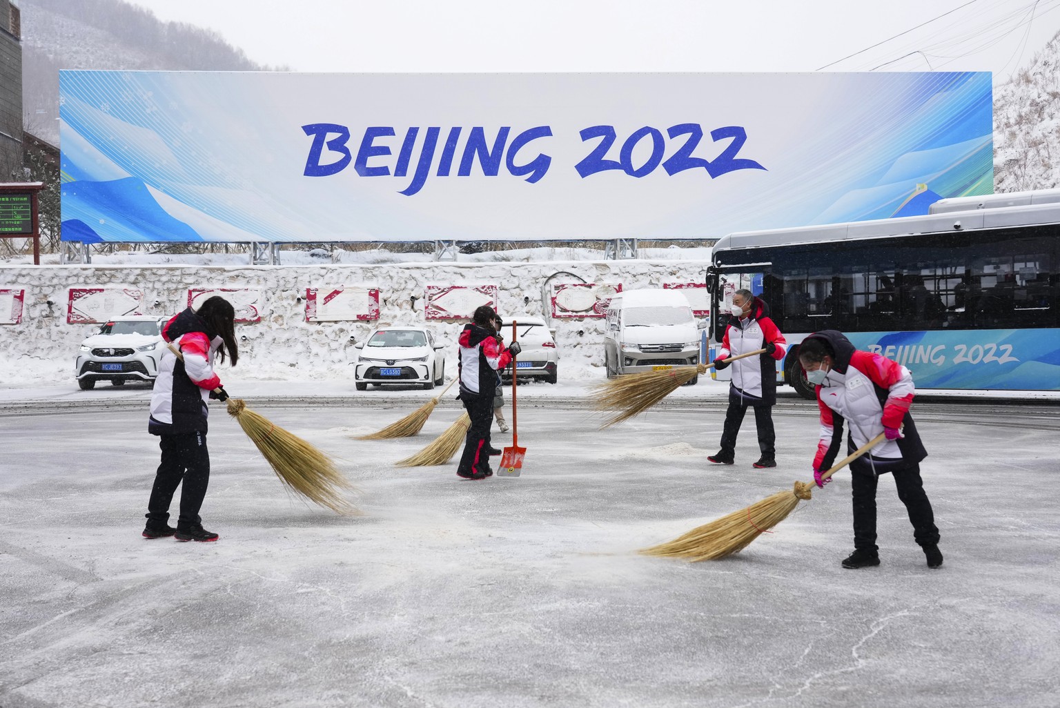 Volunteers clear snow from the bus terminal at the Zhangiiakou Media Center during the 2022 Winter Olympics, Sunday, Feb. 13, 2022, in Zhangjiakou, China. (Sean Kilpatrick/The Canadian Press via AP)
