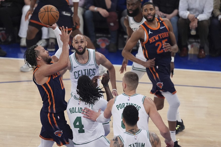 New York Knicks&#039; Jalen Brunson, left, shoots over Boston Celtics&#039; Jrue Holiday (4) and Derrick White (9) during the first half of Game 4 in the Eastern Conference semifinals of the NBA baske ...