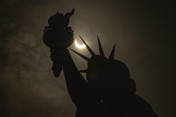 The moon partially covers the sun behind the Statue of Liberty during the a solar eclipse on the Liberty Island, Monday, April. 8, 2024, in New York. (AP Photo/Yuki Iwamura)