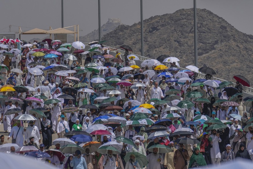 Muslim pilgrims use umbrellas to shield themselves from the sun as they arrive to cast stones at pillars in the symbolic stoning of the devil, the last rite of the annual hajj, in Mina, near the holy  ...
