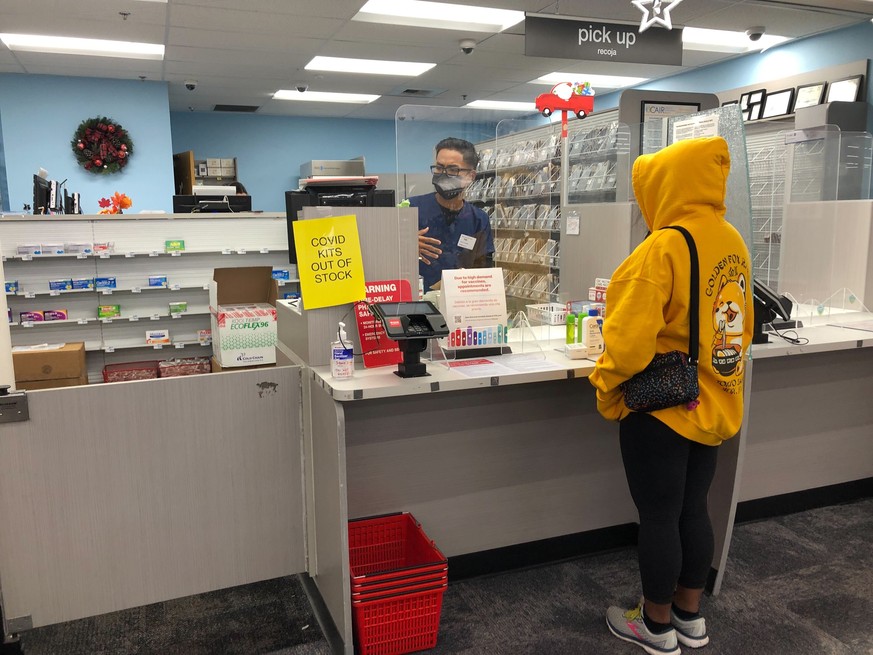 A woman waits at the pharmacy counter at a CVS on Sunset Boulevard in the Echo Park neighborhood of Los Angeles where the location is sold out of CIOVID at-home rapid test kits during the omicron surg ...