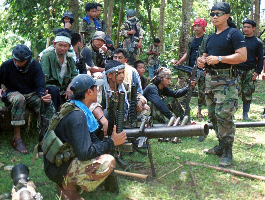 FILE - In this undated file photo, Abu Sayyaf spokesman Abu Sabaya, right foreground, is seen with his band of armed extremists. Philippine troops captured an Abu Sayyaf rebel commander blamed for yea ...