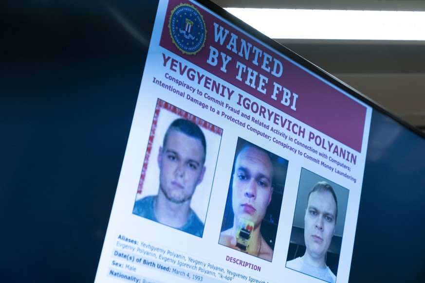Russian Yevgeniy Polyanin, wanted by the FBI, is displayed on monitors as Attorney General Merrick Garland accompanied by Deputy Attorney General Lisa Monaco and FBI Director Christopher Wray speaks a ...