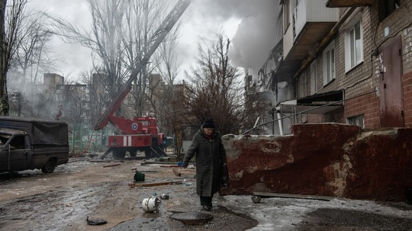 epa11037318 A local elderly woman walks past a damaged building following shelling in Donetsk, Donetsk region, eastern Ukraine, 19 December 2023. Six people were injured in Donetsk as a result of shel ...