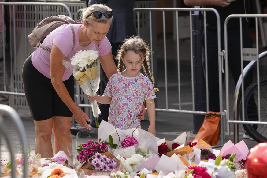 A girl and a woman place flowers as a tribute near a crime scene at Bondi Junction in Sydney, Monday, April 15, 2024, after several people were stabbed to death at a shopping on April 13. Australian p ...