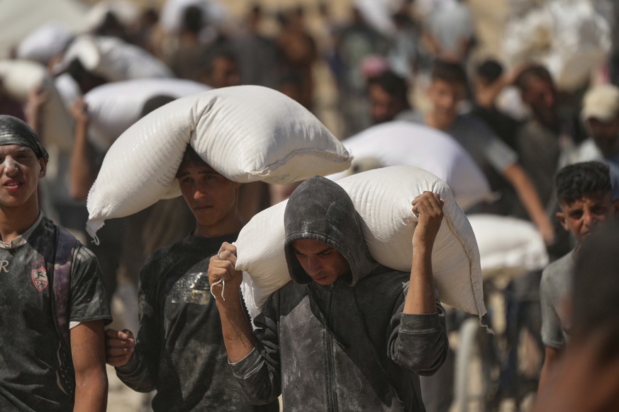 Palestinians carry sacks of flour taken from a humanitarian aid convoy en route to Gaza City, in the outskirts of Beit Lahiya, northern Gaza Strip, Friday, Aug. 1, 2025. (AP Photo/Jehad Alshrafi)
Isra ...