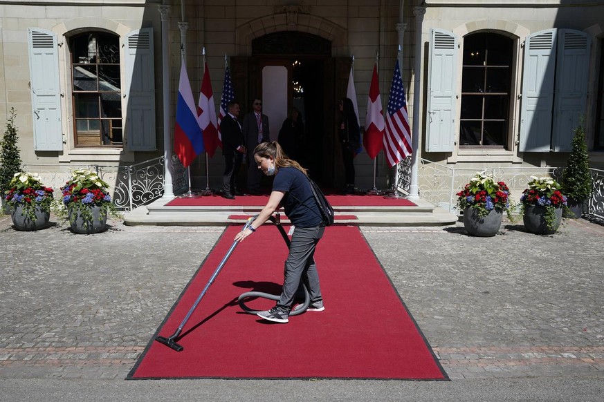 A worker vacuums the red carpet where President Joe Biden will meet Russian President Vladimir Putin, Wednesday, June 16, 2021, in Geneva, Switzerland. (AP Photo/Patrick Semansky)