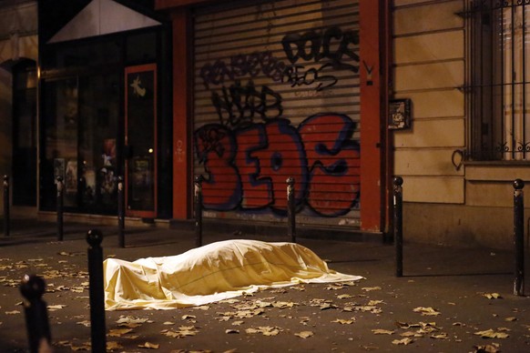 A victim under a blanket lays dead outside the Bataclan theater in Paris, Friday Nov. 13, 2015. Well over 100 people were killed in a series of shooting and explosions explosions. French President Fra ...