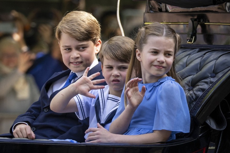 Britain&#039;s Prince George, Prince Louis and Princess Charlotte ride in a carriage.