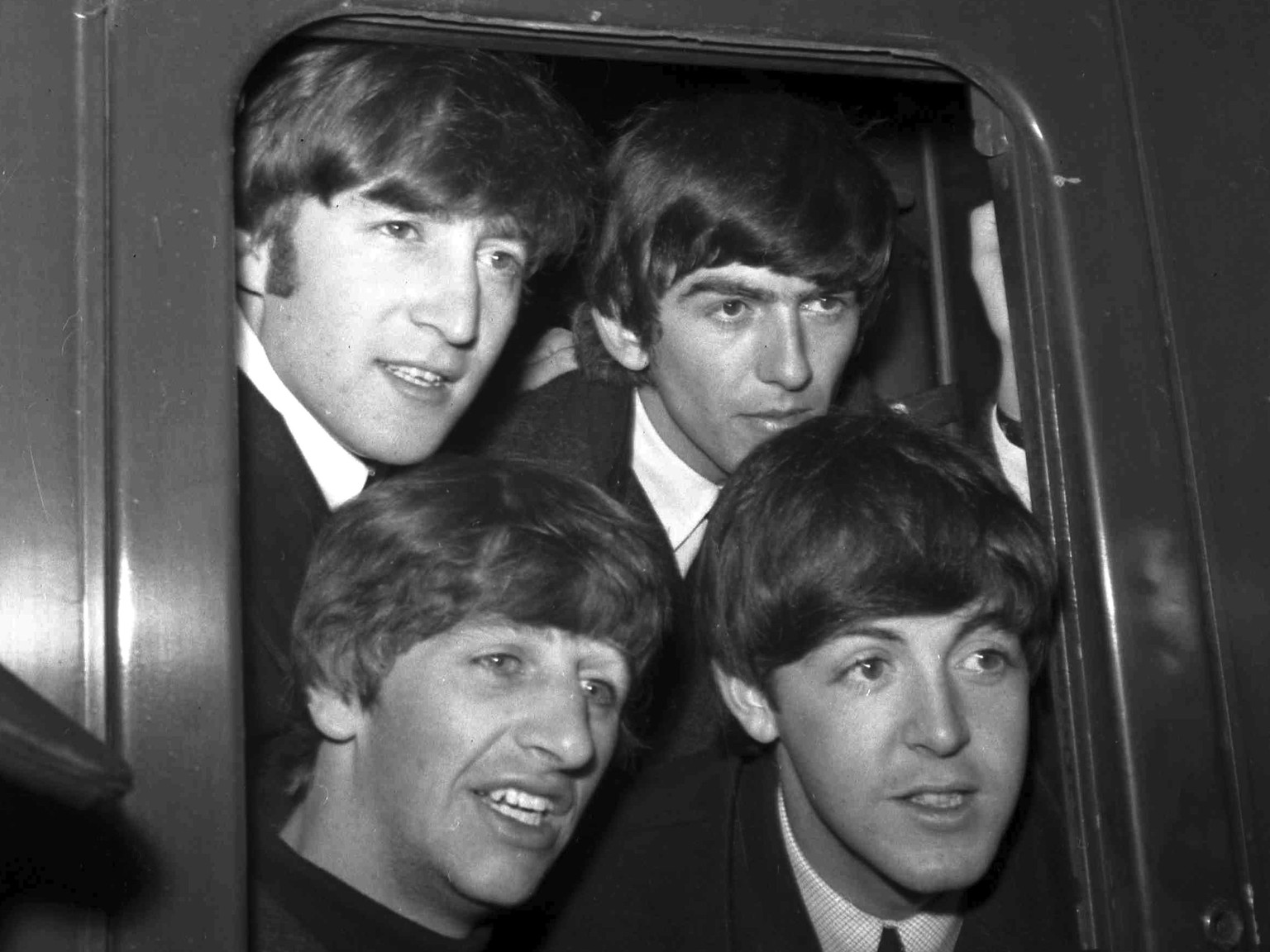 FILE - Britain&#039;s pop group The Beatles, clockwise from top left, John Lennon, George Harrison, Paul McCartney and Ringo Starr, pose in a carriage window of train before they left Paddington Stati ...