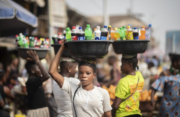 Street vendors balance trays of beverages they sell in a local market in Anambra, Nigeria, Friday, Feb. 24, 2023. Nigerian voters are heading to the polls Saturday to select a new president following  ...