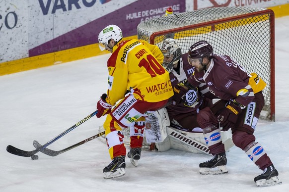 L&#039;attaquant biennois Luca Cunti, gauche, a la lutte pour le puck avec le defenseur genevois Simon Le Coultre, droite, devant le gardien genevois Robert Mayer, centre, lors du match du championnat ...