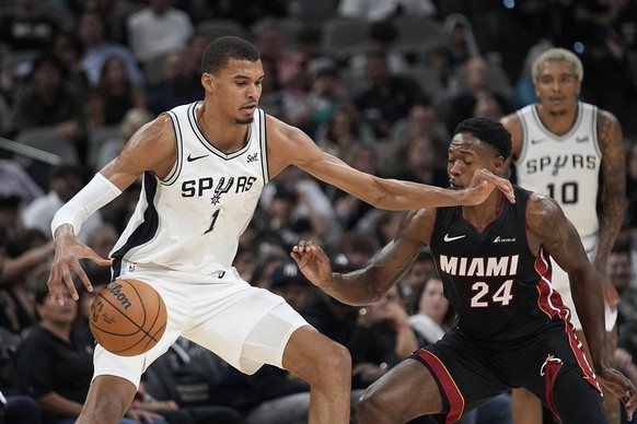 San Antonio Spurs center Victor Wembanyama (1) tries to move the ball past Miami Heat forward Haywood Highsmith (24) during the first half of a preseason NBA basketball game in San Antonio, Friday, Oc ...