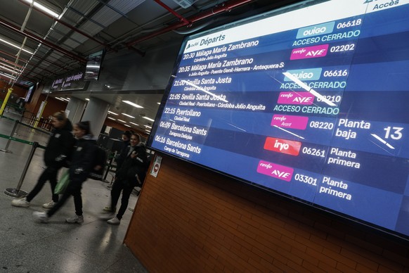 epa12659774 People walk past train departure panels showing cancellations to Seville and Malaga at Atocha station in Madrid, Spain, 18 January 2026. The Samur Emergency Team offered its assistance to  ...