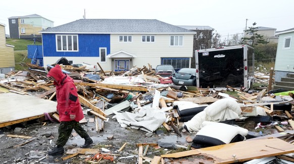 A Canadian Forces Ranger walks through the devastation of destroyed properties in Port aux Basques, Newfoundland and Labrador, Monday, Sept. 26, 2022. After surging north from the Caribbean as a major ...