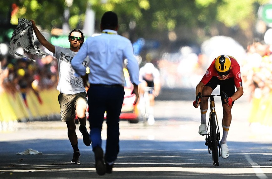 TOULOUSE, FRANCE - JULY 16: (L-R) Stage winner Jonas Abrahamsen of Norway and Team Uno-X Mobility sprints at finish line while a pro-Palestinian spontaneous bursts into the arrival area during the 112 ...