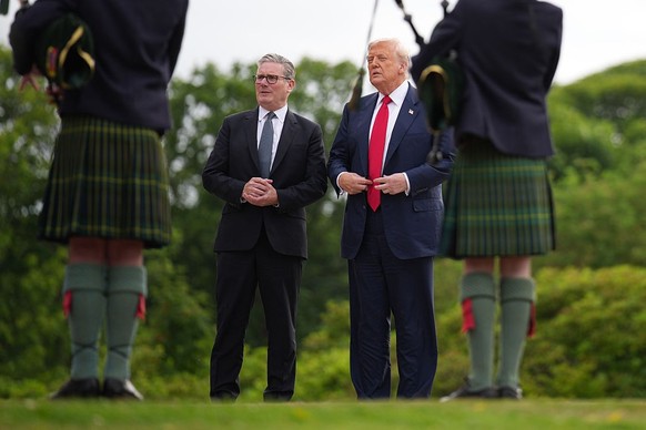 BALMEDIE, SCOTLAND - JULY 28: U.S. President Donald Trump and British Prime Minister Keir Starmer stand in front of some people playing the bagpipes at Trump International Golf Links on July 28, 2025  ...