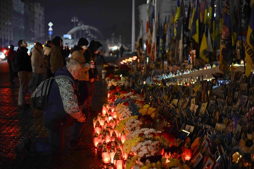 Un homme s'agenouille pour rendre hommage devant un mémorial improvisé dédié aux soldats ukrainiens et étrangers sur la place de l'Indépendance, à l'occasion du quatrième anniversaire d ...