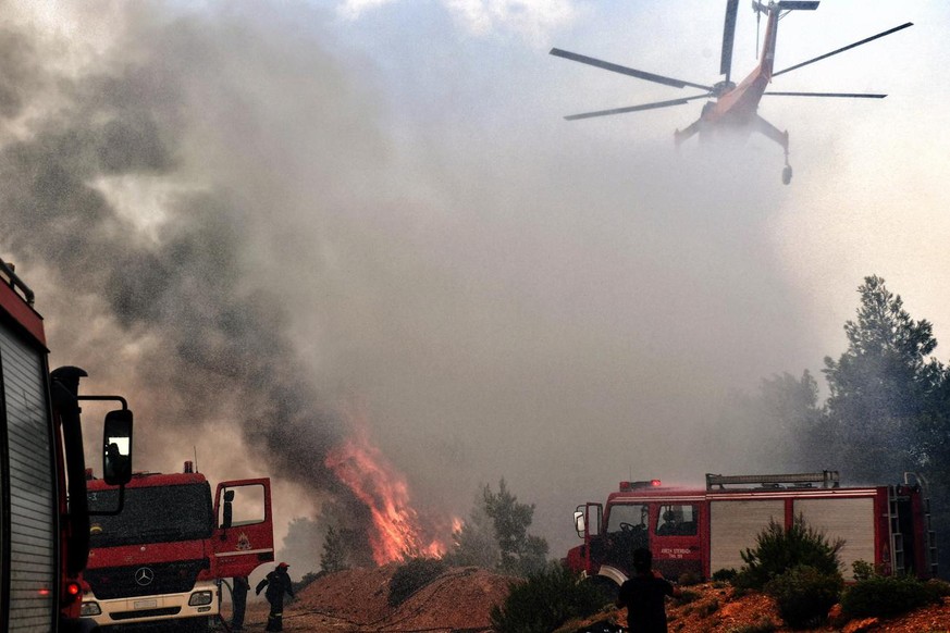 epa06908439 A firefighting helicopter and firemen try to extinguish a wildfire raging in Verori, near Loutraki city, Peloponnese, southern Greece, 24 July 2018. As a precautionary move, authorities ev ...