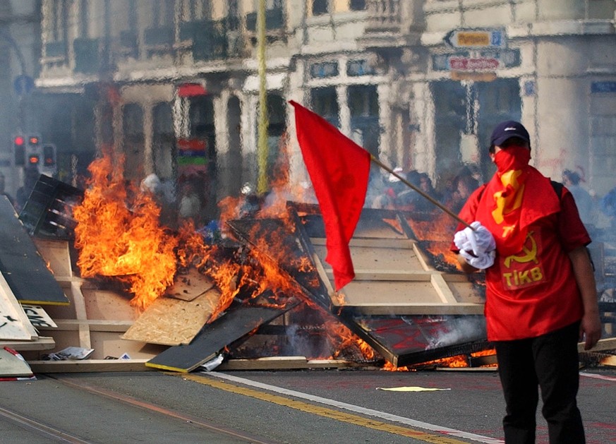 A demonstrator waves a flag in front of a buring barricade on the bridge Coulouvriniere in Geneva, Switzerland, Sunday, June 1, 2003. Several hundred anti G8 demonstrators have blocked the bridges in ...
