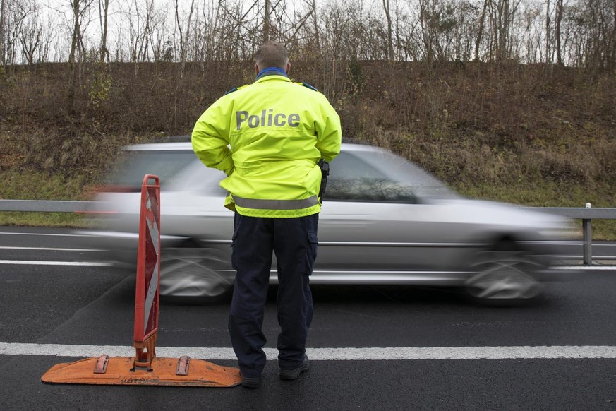 Ein Polizist beobachtet den Verkehr auf der Autobahn A5, am Montag, 29. November 2021, bei Thielle im Kanton Neuenburg. (KEYSTONE/Peter Klaunzer)