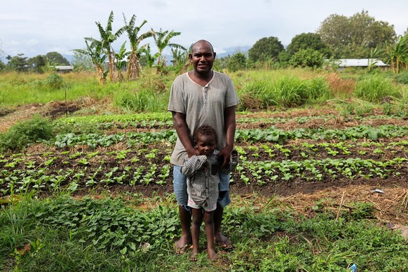 This photo taken on September 11, 2025 shows Dennis Phillip and his son Kayddy who have found dozens of US World War II unexploded bombs in the back yard of their home in Honiara. Japanese and Allied  ...