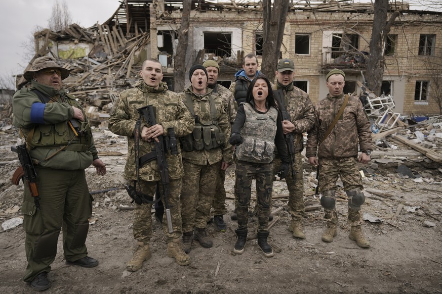 Ukrainian servicemen sing a patriotic song amid buildings destroyed during fighting between Ukrainian and Russian forces in Borodyanka, Ukraine, Tuesday, April 5, 2022.(AP Photo/Vadim Ghirda)