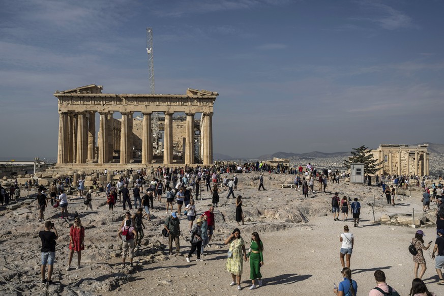 Des touristes visitent la colline de l'Acropole avec, à gauche, le temple du Parthénon, vieux de 2 500 ans.