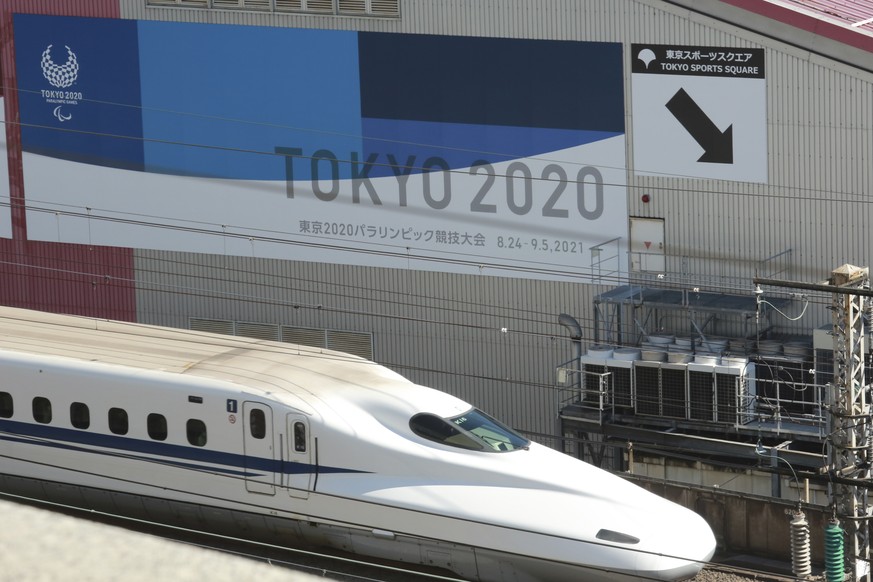 Shinkansen bullet train moves past the poster of the Paralympic Games scheduled for the summer this year, in Tokyo, Wednesday, Feb. 24, 2021. Japan began to roll out coronavirus vaccines last week, a  ...