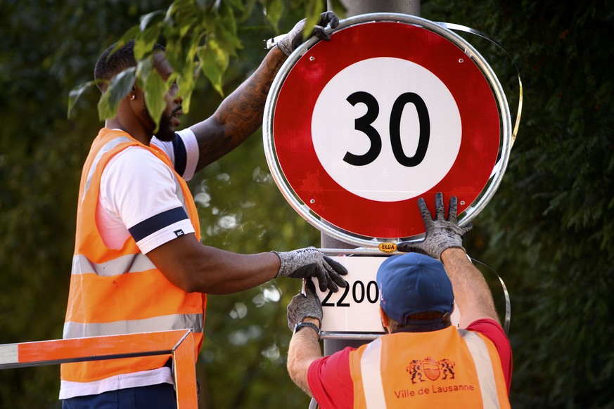 Deux employes de la ville de Lausanne mettent en place un panneau de circulation signalant l'interdiction de rouler a plus de 30km/h, de 22h00 a 06h00, ce lundi 13 septembre 2021 dans une rue de ...