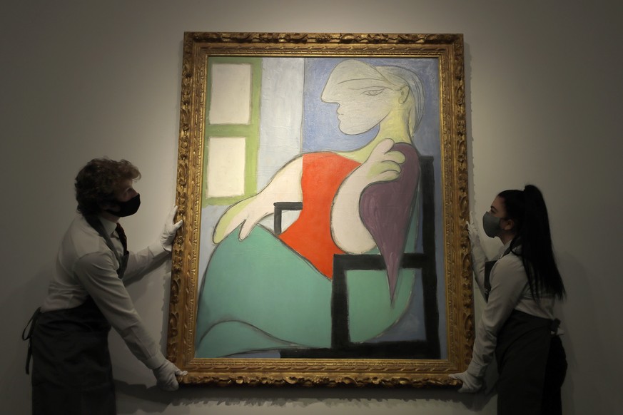 Christie&#039;s technicians adjust a Pablo Picasso painting called &#039;Femme assise pres d&#039;une fenetre&#039; at Christie&#039;s auction rooms in London, Thursday, April 22, 2021. The painting w ...