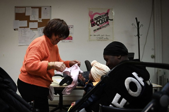 Un bénévole donne des vêtements à une mère dans un centre de l&#039;association caritative «Les Restos du cœur» à Paris, le 18 novembre 2022 (photo d&#039;archive).