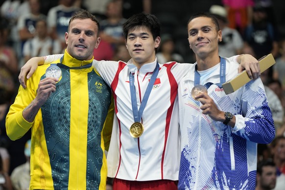 Gold medalist Pan Zhanle, center, of China, stands on the podium with silver medalist Kyle Chalmers, left, of Australia, and bronze medalist David Popovici, of Romania, following the men&#039;s 100-me ...