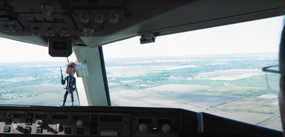 Une petite tête branlante de Donald Trump est assise sur le tableau de bord du pilote.