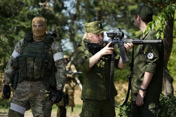 FILE - A Russian Army soldier looks through a sniper rifle scope as she and other soldiers guard a group of foreign journalists visiting a captured Ukrainian checkpoint and well-fortified trenches nea ...