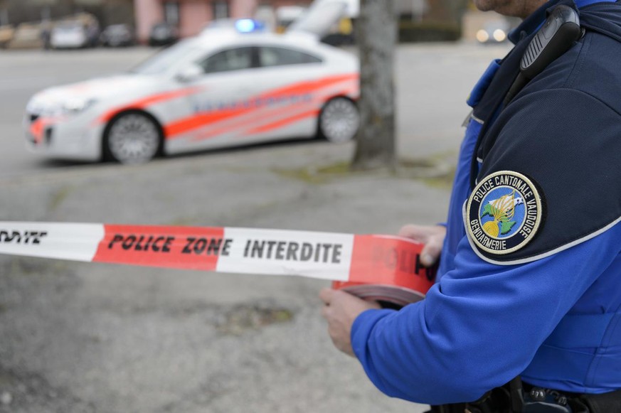 [Editor&#039;s note: photo mise-en-scene] Detail view a police officer of the cantonal police of Vaud who installs a protective strip saying &quot;police zone prohibited area&quot;, in the foreground, ...